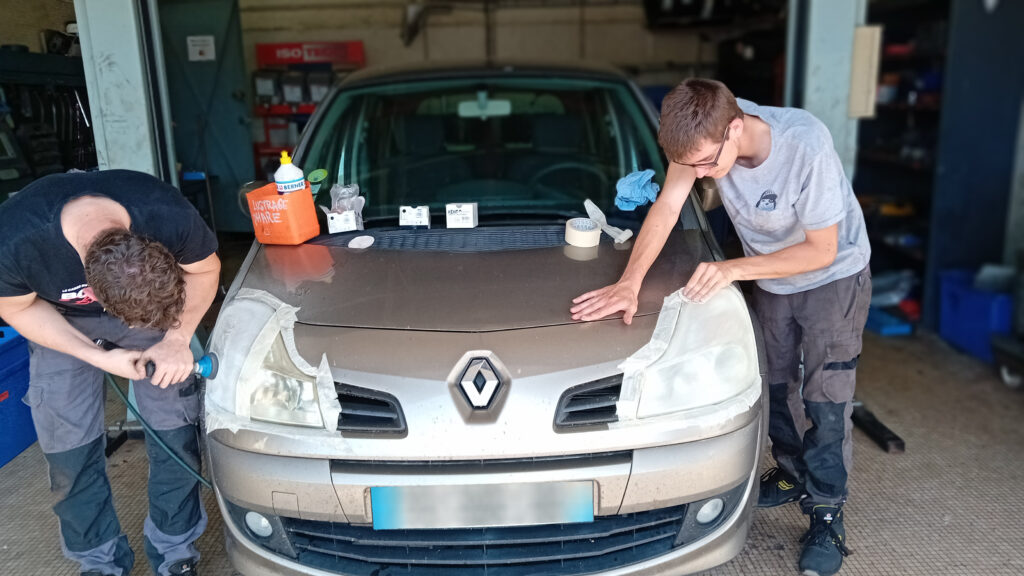 deux salariés du garage qui s'occupe d'une voiture