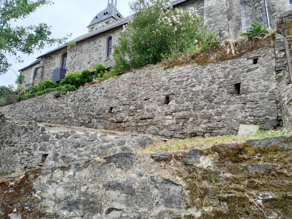 Nettoyage du mur du presbytère. Sur la partie haute le mur est propre. Sur la partie basse, la mousse et le lichen sont toujours présents.